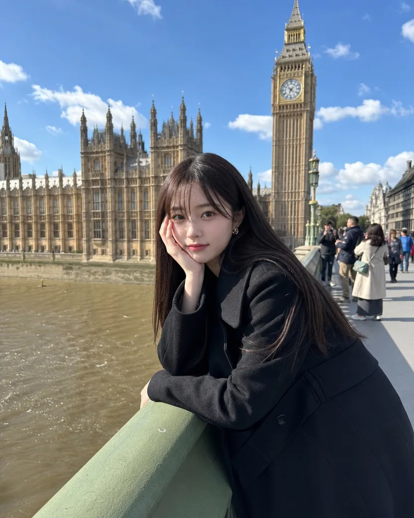 Unedited phone photo of a young woman with long dark hair and a fringe leaning on the railing of Westminster Bridge, cheek resting on her hand, with the Houses of Parliament and the clock tower behind her in flat digital colour on a bright day